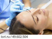 Permanent make-up for eyelashes of beautiful woman in a beauty salon. Close-up of beautician doing tattooing eyelashes. Micropigmentation treatment.. Permanent make-up for eyelashes of beautiful woman in a beauty salon. Micropigmentation treatment. Стоковое фото, агентство Ingram Publishing / Фотобанк Лори