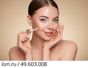 Portrait beautiful young woman with clean fresh skin. Model with foundation makeup bottle. Cosmetology, beauty and spa. Стоковое фото, агентство Ingram Publishing / Фотобанк Лори