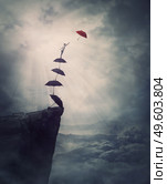 Surreal adventure, epic scene with a determined man climbing an improvised stairway of umbrellas, decided to reach a different one. Purposefulness and risk concept, on edge of a cliff, fighting fears. Стоковое фото, агентство Ingram Publishing / Фотобанк Лори