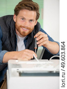 handsome man fixing a photocopier during maintenance. Стоковое фото, агентство Ingram Publishing / Фотобанк Лори