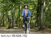 beautiful woman cycling along tree lined path. Стоковое фото, агентство Ingram Publishing / Фотобанк Лори
