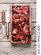 Sliced basturma or meat jerky.Beef jerky,dried beef.Armenian food. Sliced basturma or jerky on cutting board. Стоковое фото, агентство Ingram Publishing / Фотобанк Лори