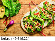 Summer vitamin salad on kitchen board.Avocado salad, tomato with garlic sauce in chard leaves.. Spring vegetable salad in chard leaves. Стоковое фото, агентство Ingram Publishing / Фотобанк Лори