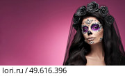 Portrait of a woman with sugar skull makeup over red background. Halloween costume and make-up. Portrait of Calavera Catrina. Стоковое фото, агентство Ingram Publishing / Фотобанк Лори