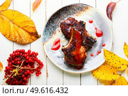 Appetizing meat on the bone grilled with viburnum syrup.. Steak with autumn viburnum,meat dish. Стоковое фото, агентство Ingram Publishing / Фотобанк Лори