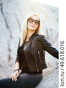 blonde girl in a black trouser suit with blue eyes on the background of a granite quarry from gray rubble. Стоковое фото, агентство Ingram Publishing / Фотобанк Лори
