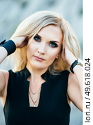 blonde girl in a black trouser suit with blue eyes on the background of a granite quarry from gray rubble. Стоковое фото, агентство Ingram Publishing / Фотобанк Лори