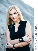 blonde girl in a black trouser suit with blue eyes on the background of a granite quarry from gray rubble. Стоковое фото, агентство Ingram Publishing / Фотобанк Лори