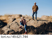 Guy and girl in caged shirts and trekking shoes on granite rocks. Стоковое фото, агентство Ingram Publishing / Фотобанк Лори