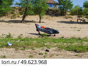 Рыбак везёт надувную лодку по берегу, река Волга, остров Зелёный, Волгоградская область, Россия (2020 год). Редакционное фото, фотограф Андрей Цыганков / Фотобанк Лори