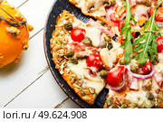 Pizza with sausage, tomato and capers on a pumpkin tortilla. Autumn pumpkin pizza. Стоковое фото, агентство Ingram Publishing / Фотобанк Лори
