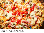 Pizza with sausage, tomato and capers on a pumpkin tortilla. Autumn delicious pumpkin pizza. Стоковое фото, агентство Ingram Publishing / Фотобанк Лори