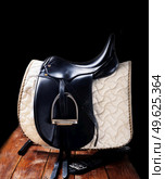 Black professional  leather dressage saddle in complete with nice saddle cloth and girth puted at saddle rack travel. equestrian concept. Стоковое фото, агентство Ingram Publishing / Фотобанк Лори
