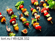 Festive snack of shrimps, jamon, fruits and vegetables on wooden skewers.. Wooden skewers with shrimps, meat and fruits. Стоковое фото, агентство Ingram Publishing / Фотобанк Лори