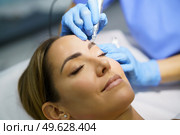 Permanent make-up for eyebrows of beautiful woman in a beauty salon. Close-up of beautician doing tattooing eyebrow. Micropigmentation treatment.. Permanent make-up for eyebrows of beautiful woman in a beauty salon. Micropigmentation treatment. Стоковое фото, агентство Ingram Publishing / Фотобанк Лори