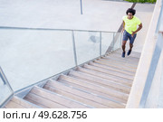 From above of fit African American male runner jogging up staircase during cardio training in city in summer. Black sportsman running upstairs in the city. Стоковое фото, агентство Ingram Publishing / Фотобанк Лори