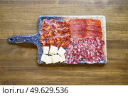 Top view of Iberian cured meats platter. A typical dish of Spanish cuisine. with crackers placed on board on lumber restaurant table. Iberian cured meats platter. A typical dish of Spanish cuisine. Стоковое фото, агентство Ingram Publishing / Фотобанк Лори