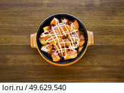 Top view of a delicious plate of patatas bravas, a typical Spanish dish, garnished with spicy sauce and served in a bowl on a wooden table in a restaurant.. Plate of patatas bravas, a typical Spanish dish, on restaurant t. Стоковое фото, агентство Ingram Publishing / Фотобанк Лори