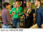 Gleeful diverse man and women with alcohol beverages smiling and talking while spending weekend day in bar together. Happy friends chatting in a beautiful bar. Стоковое фото, агентство Ingram Publishing / Фотобанк Лори