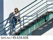 Young black female with afro braids on an urban staircase, carrying a skateboard wearing sunglasses.. Young black female with afro braids and sunglasses on an urban staircase, carrying a skateboard. Стоковое фото, агентство Ingram Publishing / Фотобанк Лори