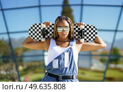 Black young woman dressed casual, looking at camera with modern sunglasses and a skateboard.. Black woman dressed casual, looking at camera with modern sunglasses and a skateboard. Стоковое фото, агентство Ingram Publishing / Фотобанк Лори