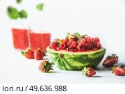 Watermelon halve served with red summer fruits, berries and red juice: strawberries and raspberries  at white background. Healthy summer refreshing. Front view. Стоковое фото, агентство Ingram Publishing / Фотобанк Лори