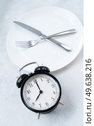 Intermitted farsting diet concept - empty plate with fork and knife and timer. Intermitted farsting diet concept. Стоковое фото, агентство Ingram Publishing / Фотобанк Лори
