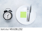 Intermitted farsting diet concept - empty plate with fork and knife and timer. Intermitted farsting diet concept. Стоковое фото, агентство Ingram Publishing / Фотобанк Лори