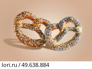 Two Bavarian pretzels with sesame and poppy seeds at pale brown background. Delicious traditional German buns. Bakery items flying. Levitation concept. Front view. Стоковое фото, агентство Ingram Publishing / Фотобанк Лори
