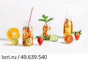 Various infused water bottles and ingredients: orange, cucumber, grapefruit, lime, strawberry and mint leaves at white background. Summer refreshing drink with fresh fruits. Healthy lifestyle. Стоковое фото, агентство Ingram Publishing / Фотобанк Лори