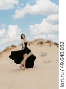 girl in a black long dress in a sandy desert under a blue sky. Стоковое фото, агентство Ingram Publishing / Фотобанк Лори