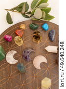 Gemstones minerals over wooden life flower chart. Magic healing Rock and moon stone for Reiki Crystal Ritual, Witchcraft, spiritual esoteric practice. Healing crystals on brown background. Стоковое фото, агентство Ingram Publishing / Фотобанк Лори