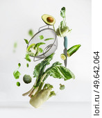 Balancing flying green vegetables ingredients: pak choi, avocado, fennel, bell pepper broccoli, edamame, turnip cabbage with sieve and kitchen knife at white background. Levitation food concept. Стоковое фото, агентство Ingram Publishing / Фотобанк Лори