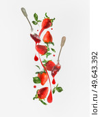 Creative strawberry jam concept with flying berries, spoons and jam splash at white background.  Front view. Levitation food. Стоковое фото, агентство Ingram Publishing / Фотобанк Лори
