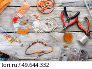 orange set for handmade jewelry with necklace  around white old style wooden background. top view. Стоковое фото, агентство Ingram Publishing / Фотобанк Лори