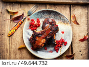Meat on the bone baked with viburnum syrup on rustic wooden table. Grilled pork with viburnum. Стоковое фото, агентство Ingram Publishing / Фотобанк Лори