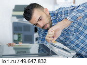 man fixing photocopying machine. Стоковое фото, агентство Ingram Publishing / Фотобанк Лори