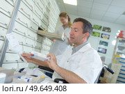disabled male pharmacist choosing storing medicines. Стоковое фото, агентство Ingram Publishing / Фотобанк Лори
