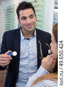 optician showing customer choice of eyeglasses or contact lenses. Стоковое фото, агентство Ingram Publishing / Фотобанк Лори