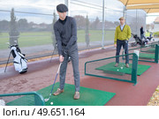 people practise golf at a city centre golf driving range. Стоковое фото, агентство Ingram Publishing / Фотобанк Лори