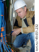 senior worker twisting tie around bundle of cable trunking. Стоковое фото, агентство Ingram Publishing / Фотобанк Лори
