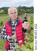 winemaker standing by his vineyard with a bottle of wine. Стоковое фото, агентство Ingram Publishing / Фотобанк Лори