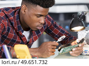 male worker with magnifying glass during electronic. Стоковое фото, агентство Ingram Publishing / Фотобанк Лори