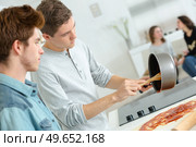 young men preparing meal girlfriends sat down chatting. Стоковое фото, агентство Ingram Publishing / Фотобанк Лори