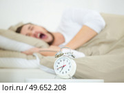 young man in bed yawning while the alarm is ringing. Стоковое фото, агентство Ingram Publishing / Фотобанк Лори