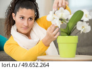 young beautiful brunette woman touching flowers at home. Стоковое фото, агентство Ingram Publishing / Фотобанк Лори