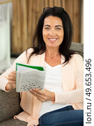 woman doing crosswords sitting on couch. Стоковое фото, агентство Ingram Publishing / Фотобанк Лори