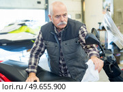 mature man cleaning a motorbike. Стоковое фото, агентство Ingram Publishing / Фотобанк Лори