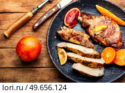 Meat steak cooked in oranges. Cutting in slices flank steak. Meat in citrus on old wooden table. Meat steak fried with citrus fruits. Стоковое фото, агентство Ingram Publishing / Фотобанк Лори