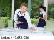 waiter setting formal dinner table. Стоковое фото, агентство Ingram Publishing / Фотобанк Лори